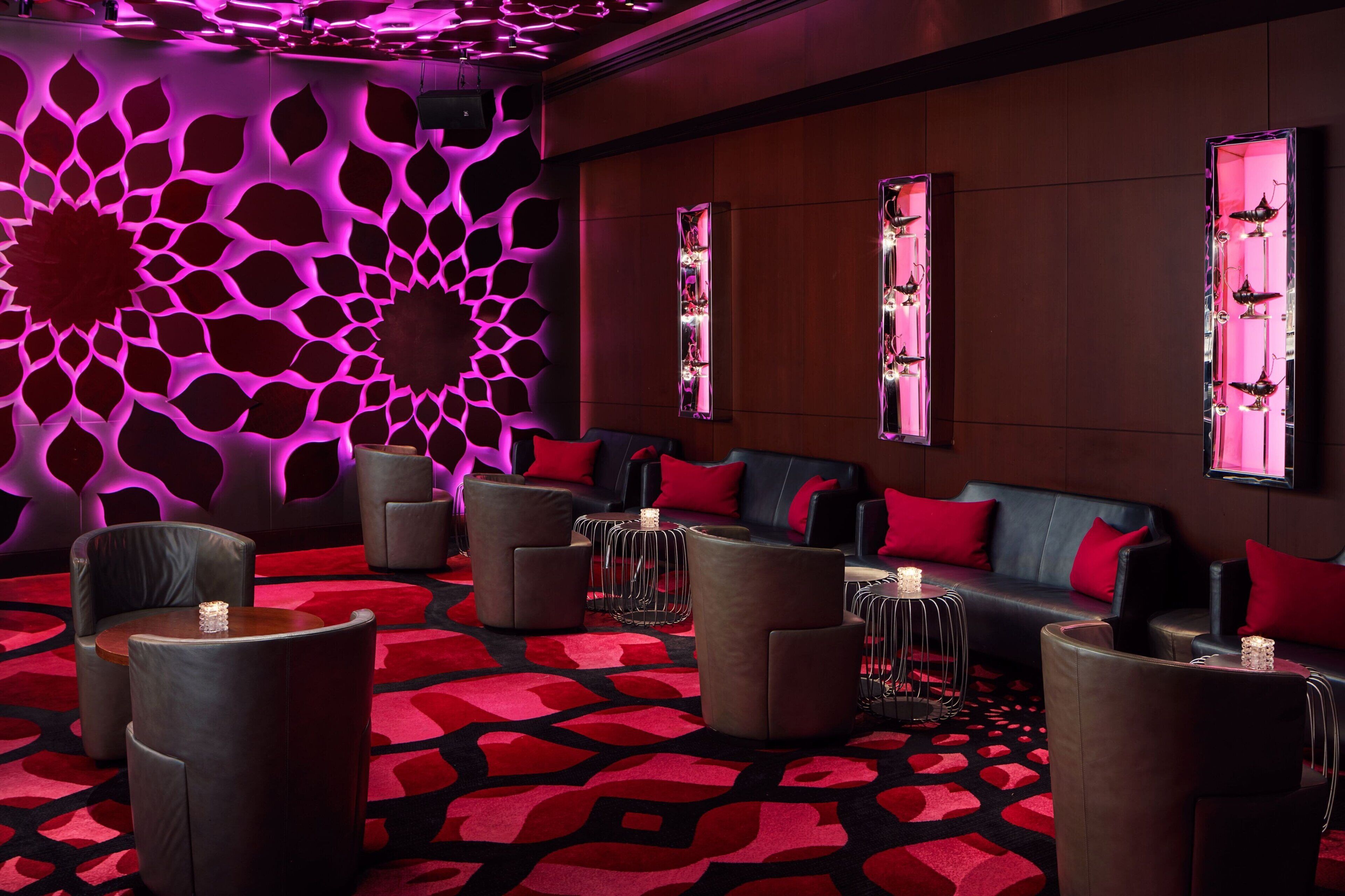 A modern lounge area with a patterned wall, leather seating, and decorative lighting.
