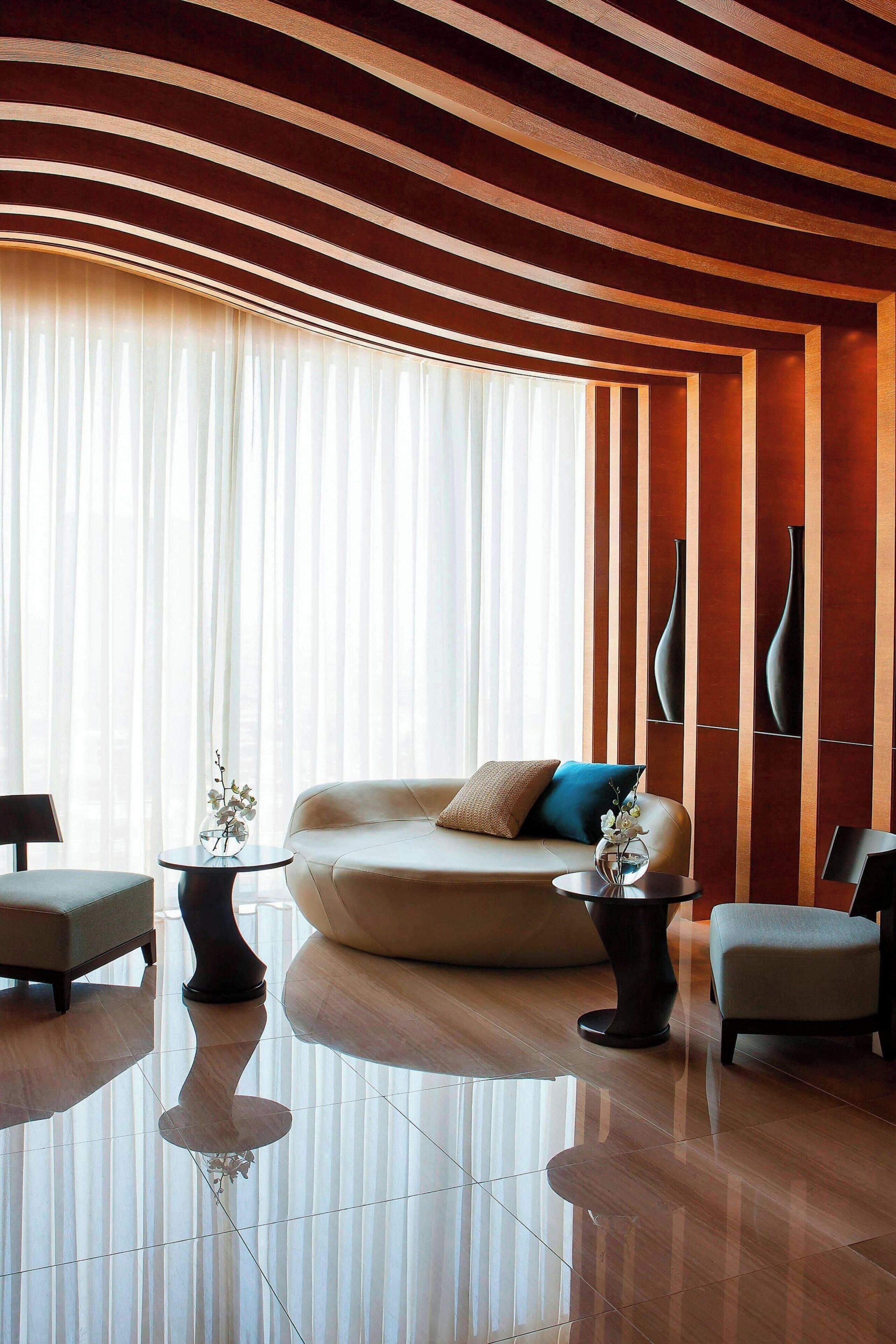 A modern living room with a sofa, two armchairs, a coffee table, and a vase of flowers.