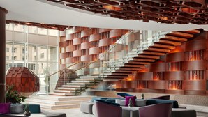 A modern lobby with a staircase, seating area, and large windows. - JW Marriott Absheron Baku (Baku)