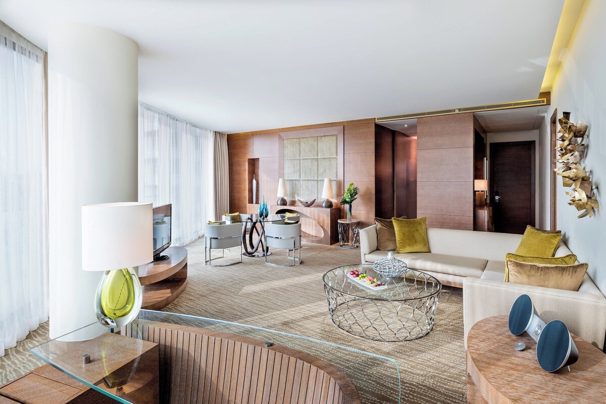 A modern hotel room with a sofa, coffee table, and a TV.