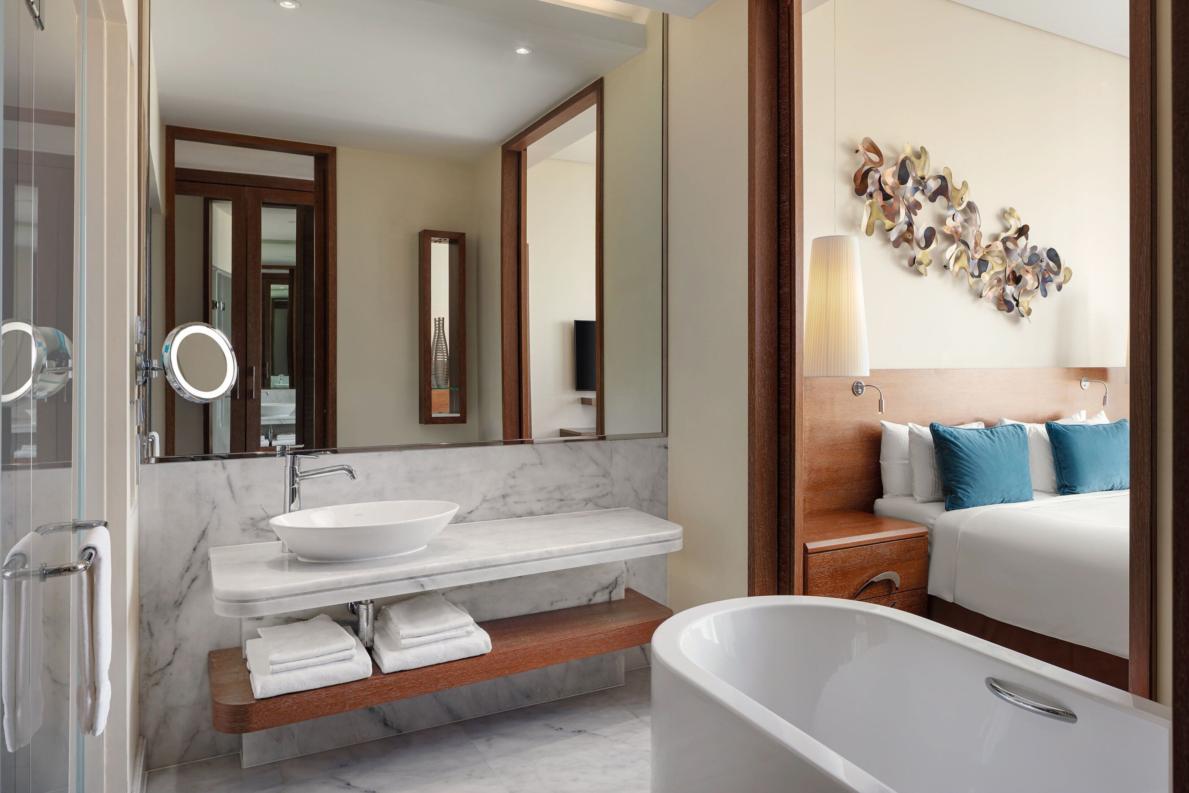 A modern bathroom with a marble sink, a freestanding bathtub, and a wooden vanity.