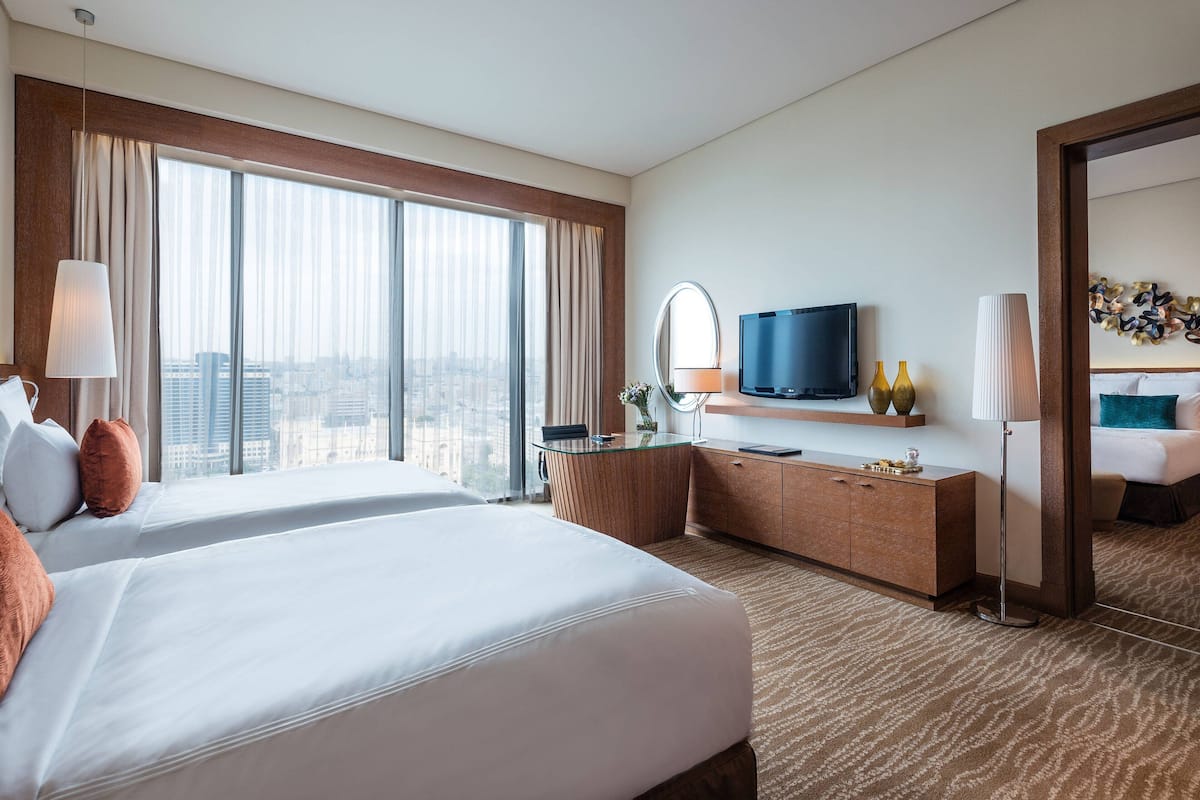 A hotel room with a large bed, a desk, a TV, and a view of the city.