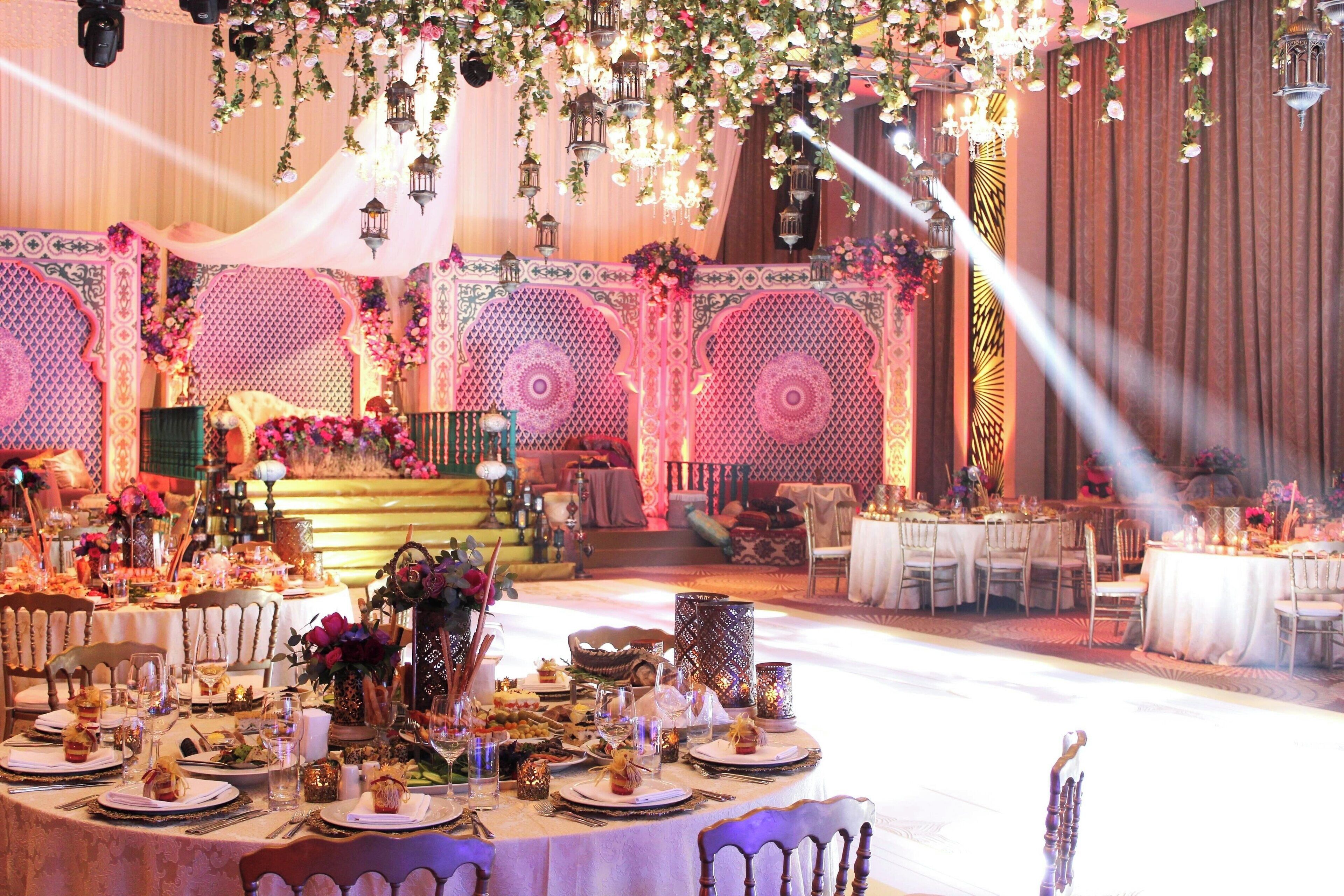 A banquet hall with round tables set for a formal event, decorated with floral arrangements and elegant table settings.