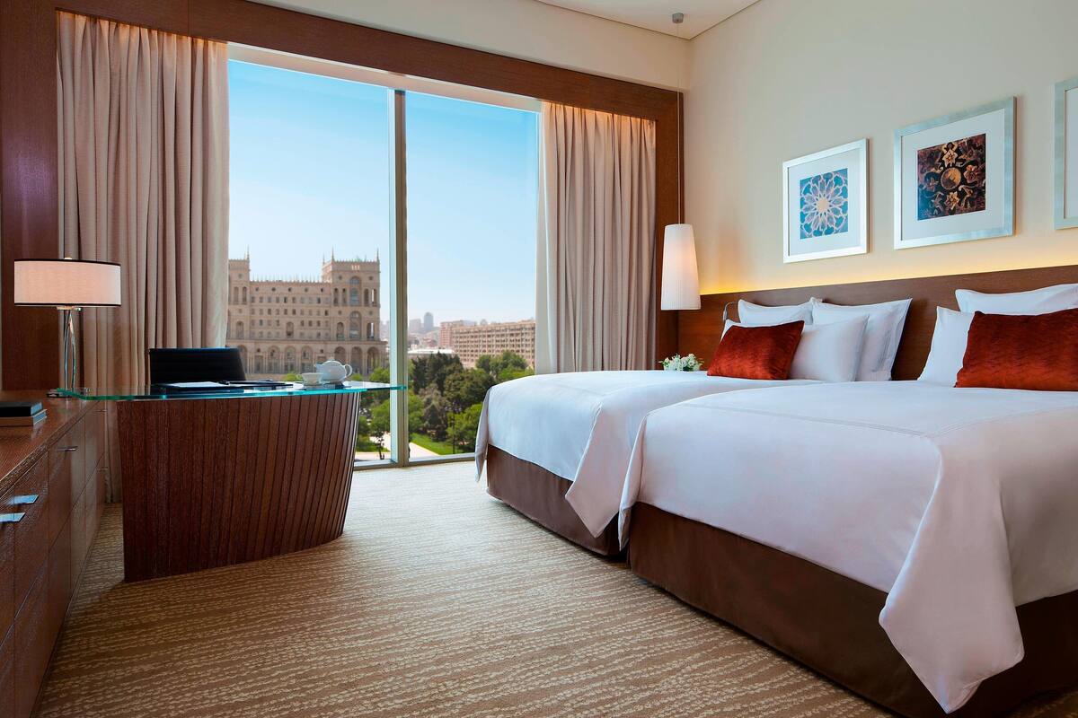 A hotel room with a large bed, a desk, and a view of a historic building.