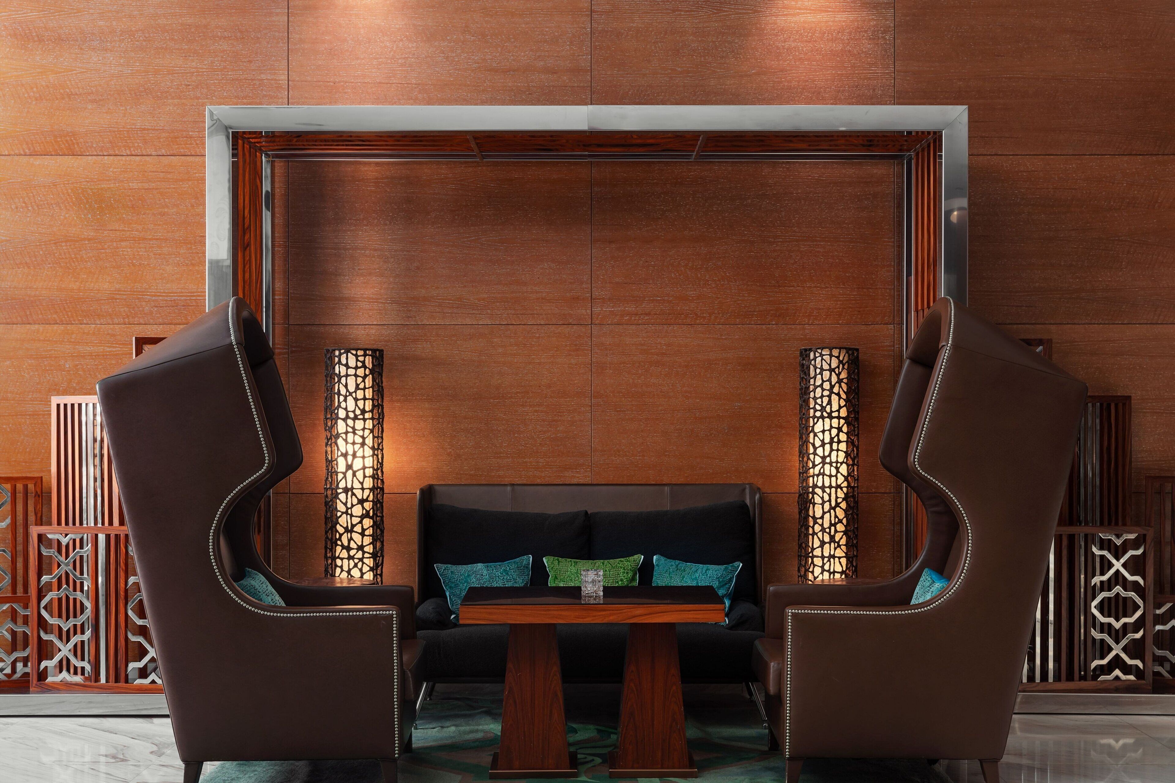 A modern room with a sofa and two armchairs, a wooden table, and decorative panels.