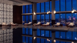 A modern indoor pool area with lounge chairs and large windows offering city views. - JW Marriott Absheron Baku (Baku)