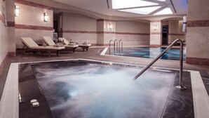 Un área de spa con un jacuzzi, sillones reclinables y una piscina.