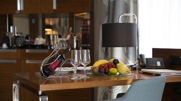 Habitación de hotel con un escritorio de madera, frutera, lámpara y teléfono.