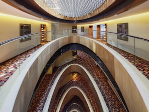 A multi-level interior with glass railings, a patterned floor, and a curved ceiling.