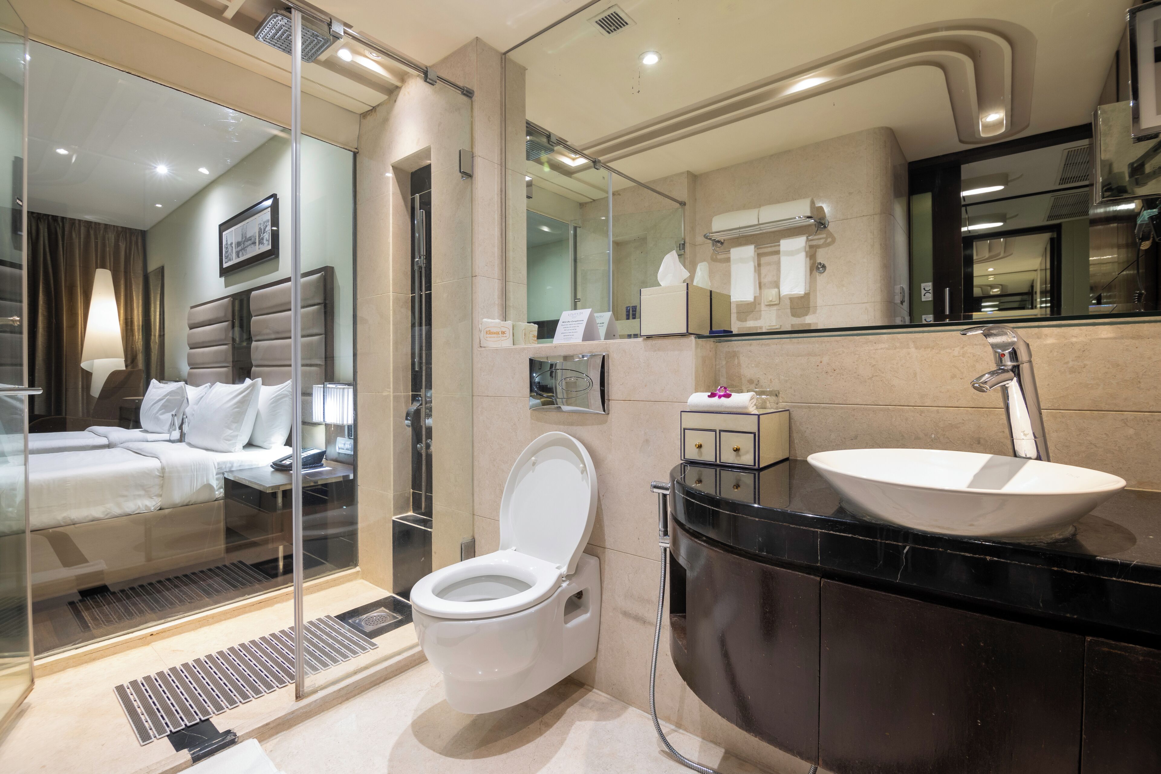 A modern bathroom with a glass-enclosed shower, a white toilet, and a black vanity with a large sink.