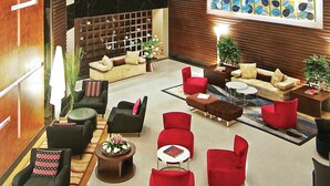 Un moderno vestíbulo de hotel con varias zonas de estar, un amplio ventanal decorativo y un techo alto.