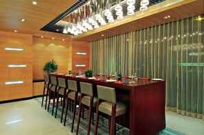 Un comedor moderno con una larga mesa de madera, varias sillas y una planta decorativa.