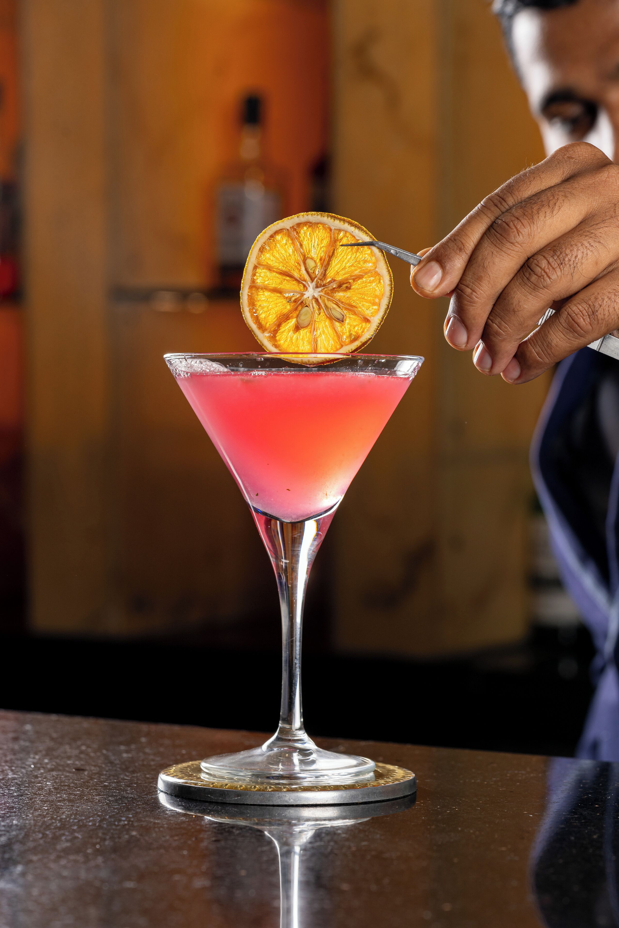 En cocktail i et martini-glas med et skive appelsin som pynt.