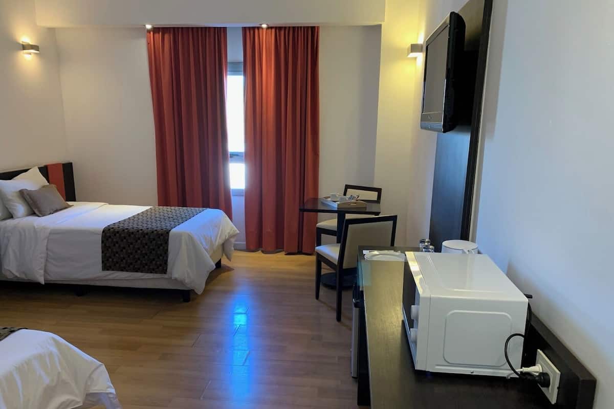 Habitación de hotel con cama, escritorio, silla, microondas y televisión.