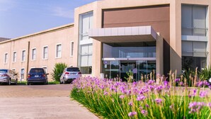 A modern building with a flat roof, large windows, and a parking area with cars.