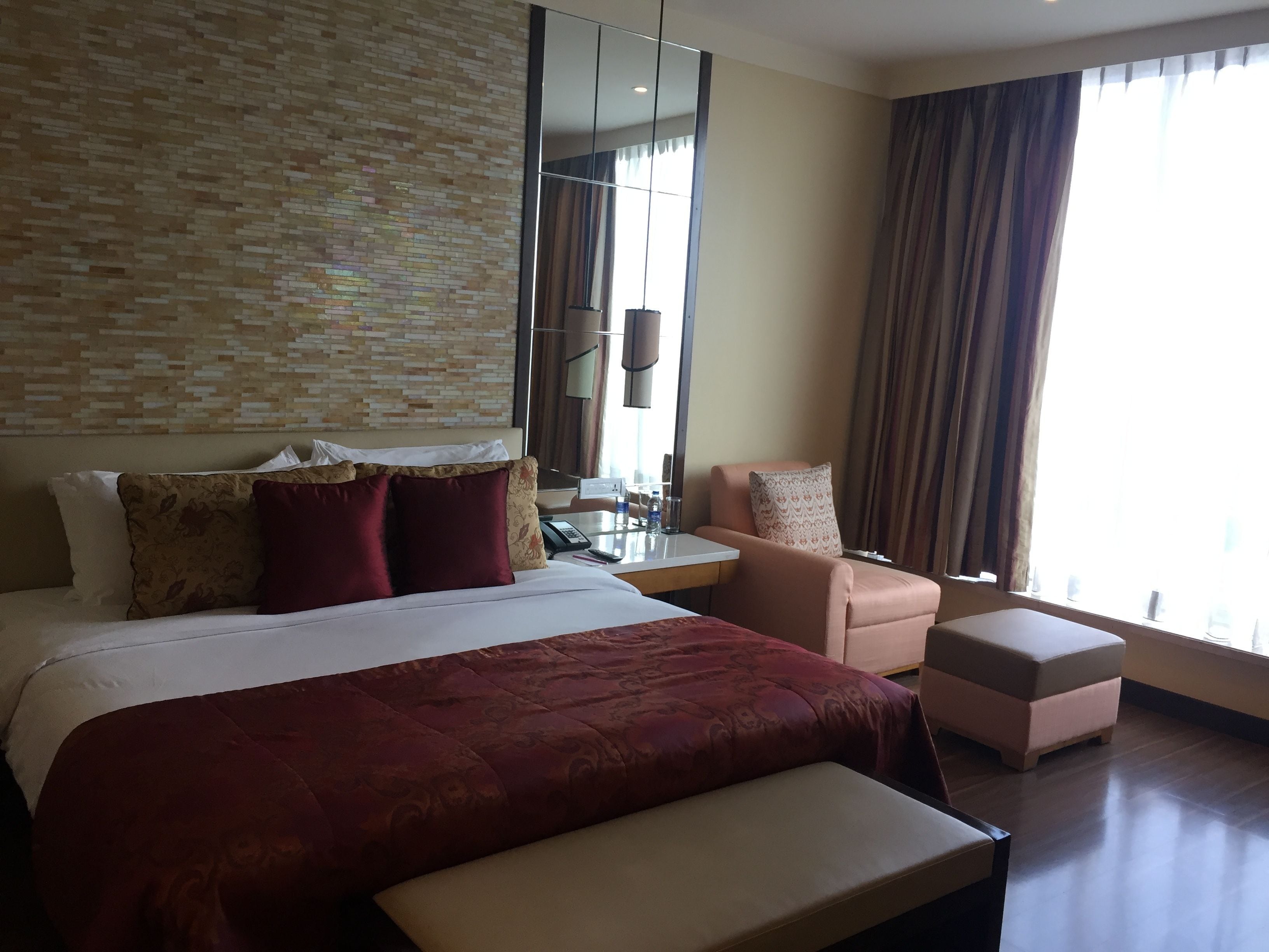 A hotel room with a large bed, a desk, a chair, and a small table.