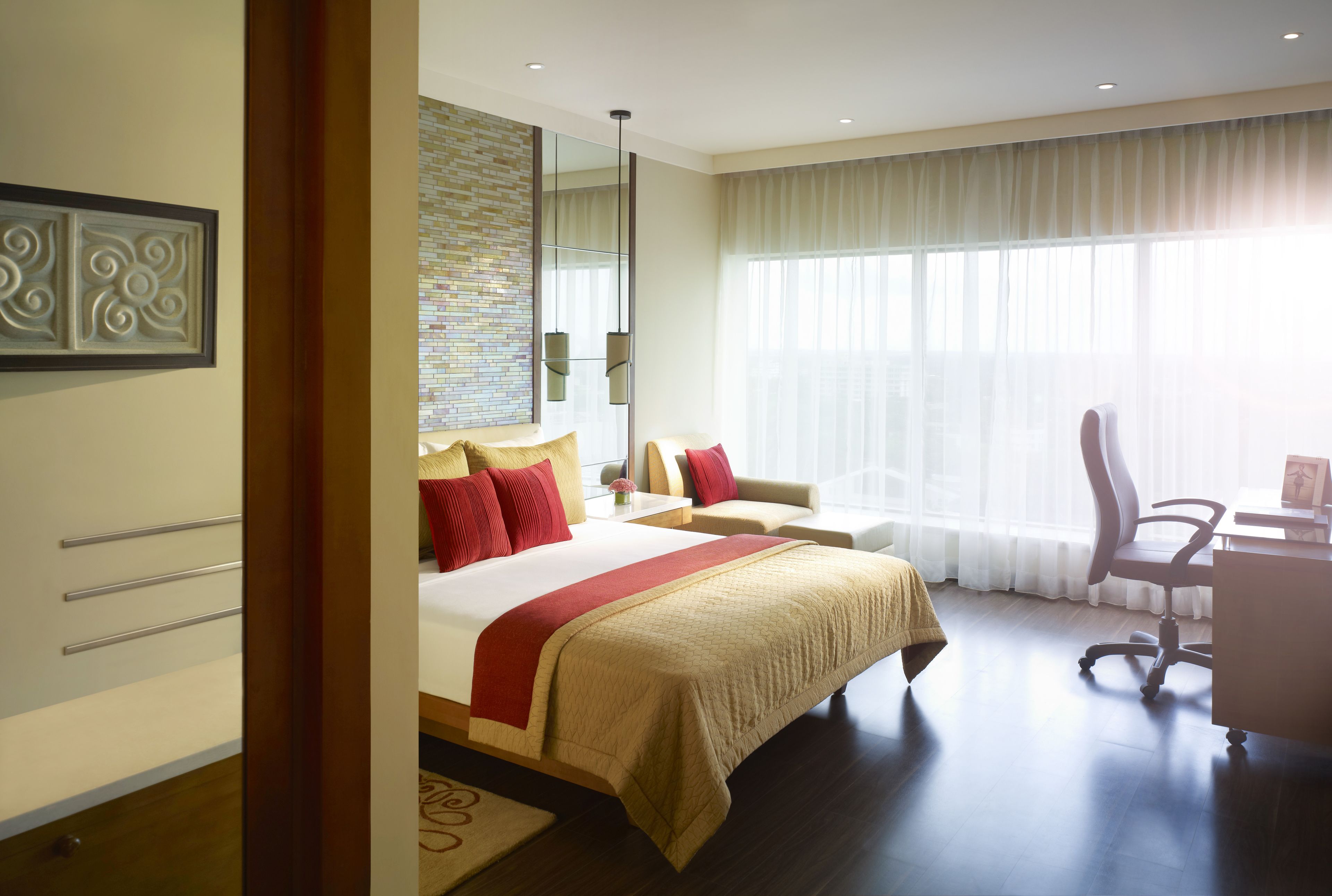 A modern hotel room with a large bed, a desk, and a chair.
