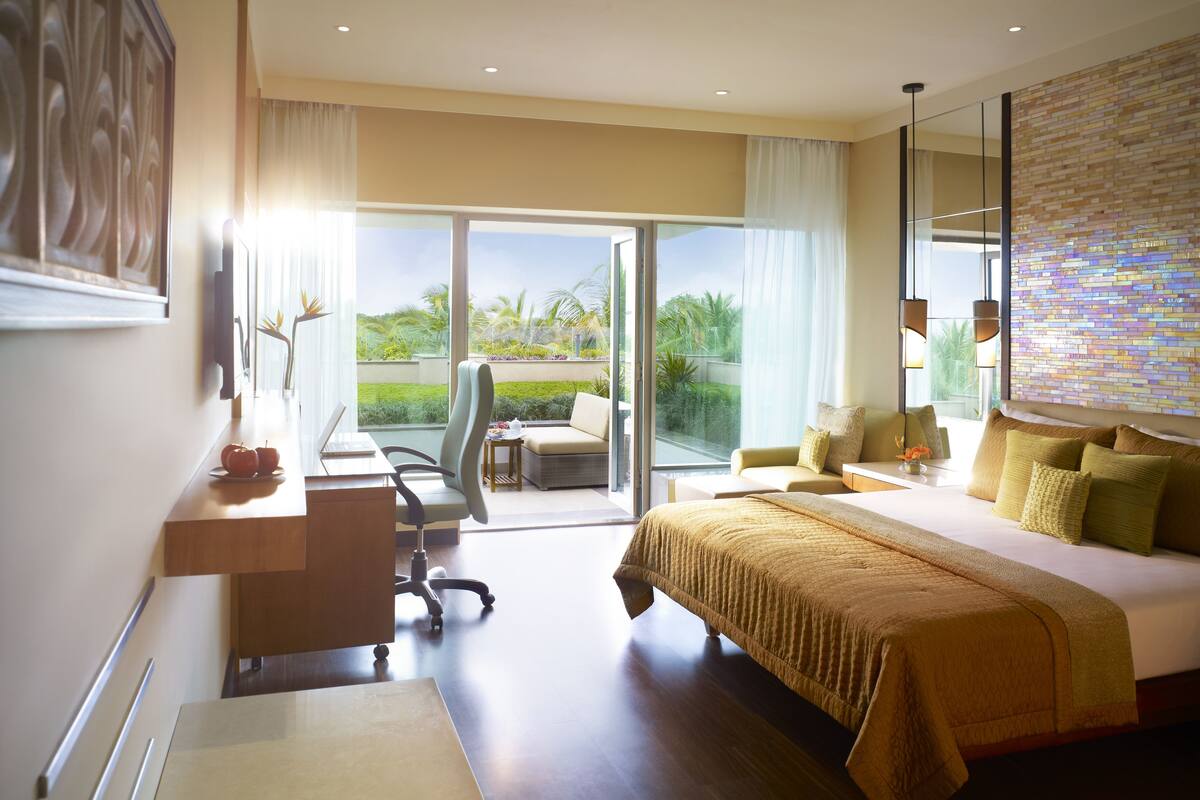 Quarto de hotel com uma cama grande, uma escrivaninha, uma cadeira e vista para o exterior.