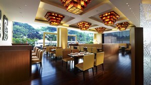 A spacious restaurant with high ceilings, multiple dining areas, and large windows offering a view of the outdoors. - Vivanta Coimbatore (Coimbatore)