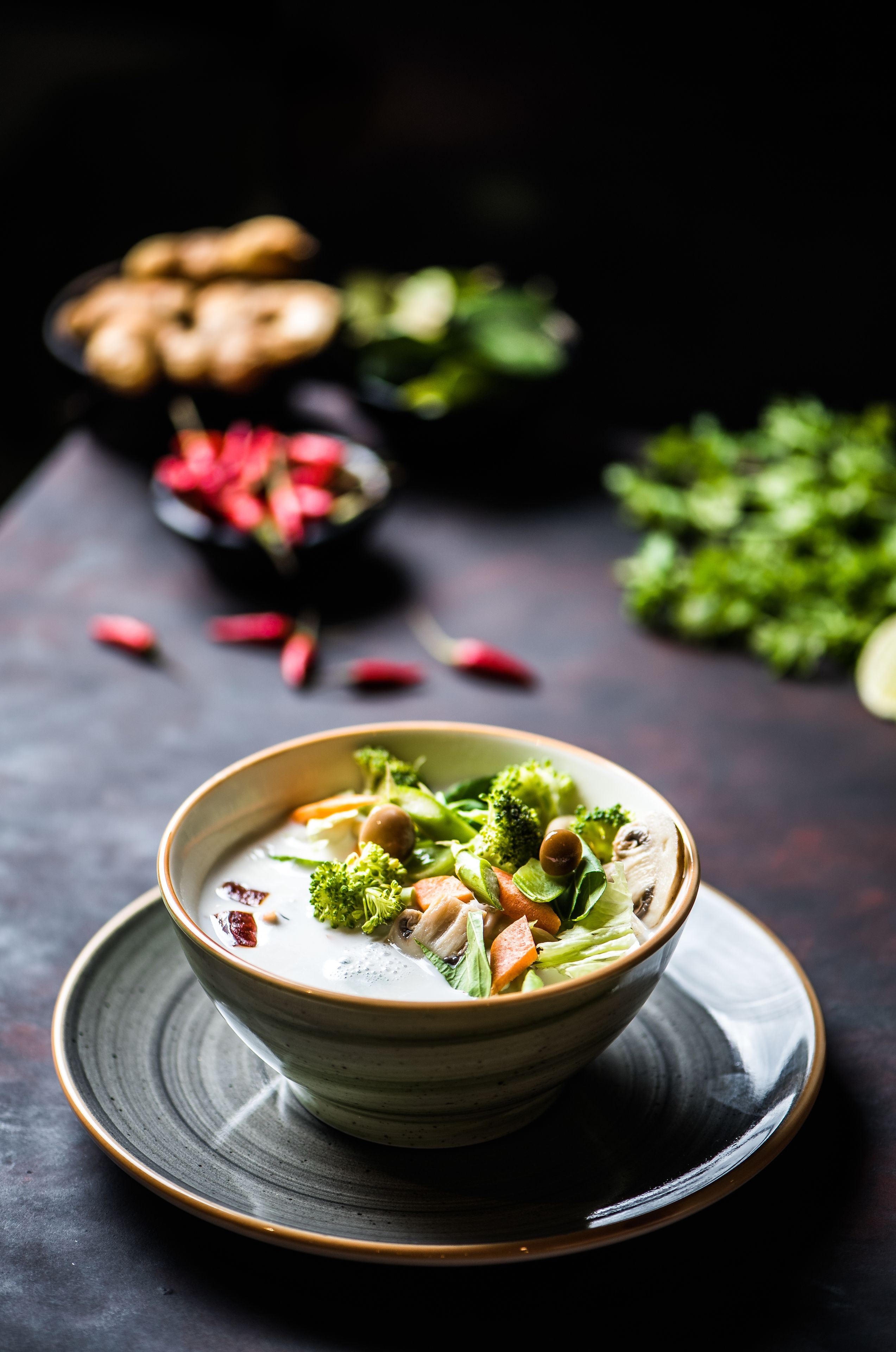 A bowl of soup with vegetables and nuts on a plate.