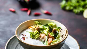 Un bol de soupe aux légumes et aux noix, servi sur une assiette.