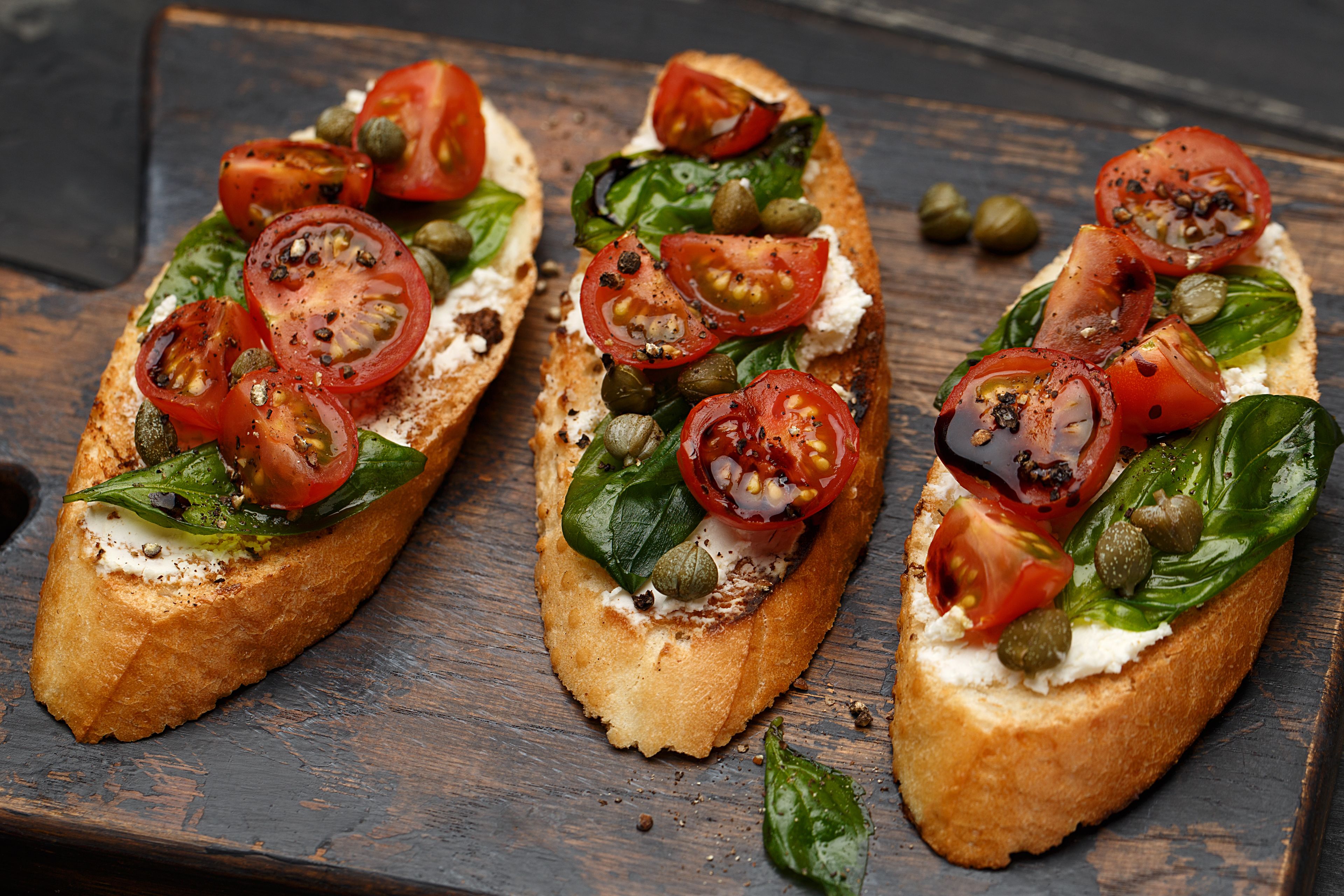Three pieces of bruschetta on a wooden board.
