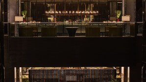 Vestíbulo de hotel de varios niveles con zona de comedor, asientos y una fuente.