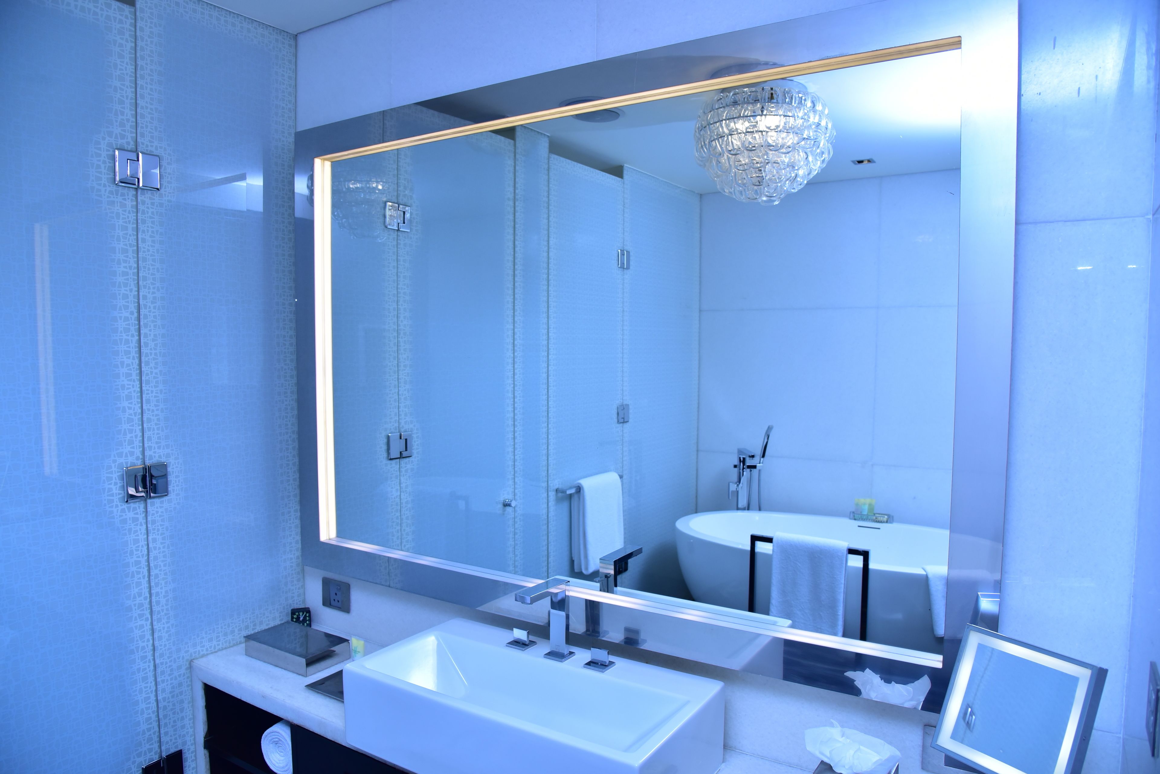 A modern bathroom with a large mirror, a sink, and a toilet.