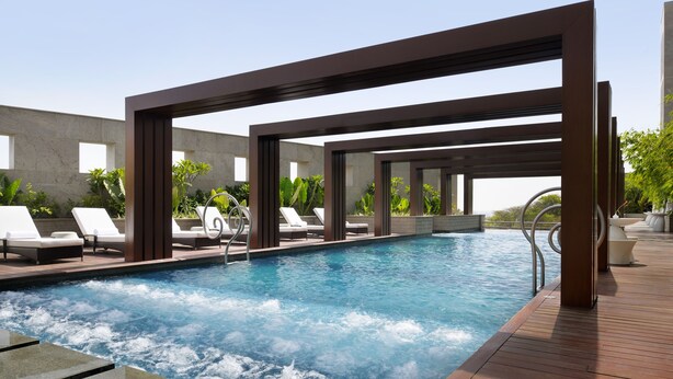 Un área de piscina moderna con sillas de descanso y una terraza de madera.