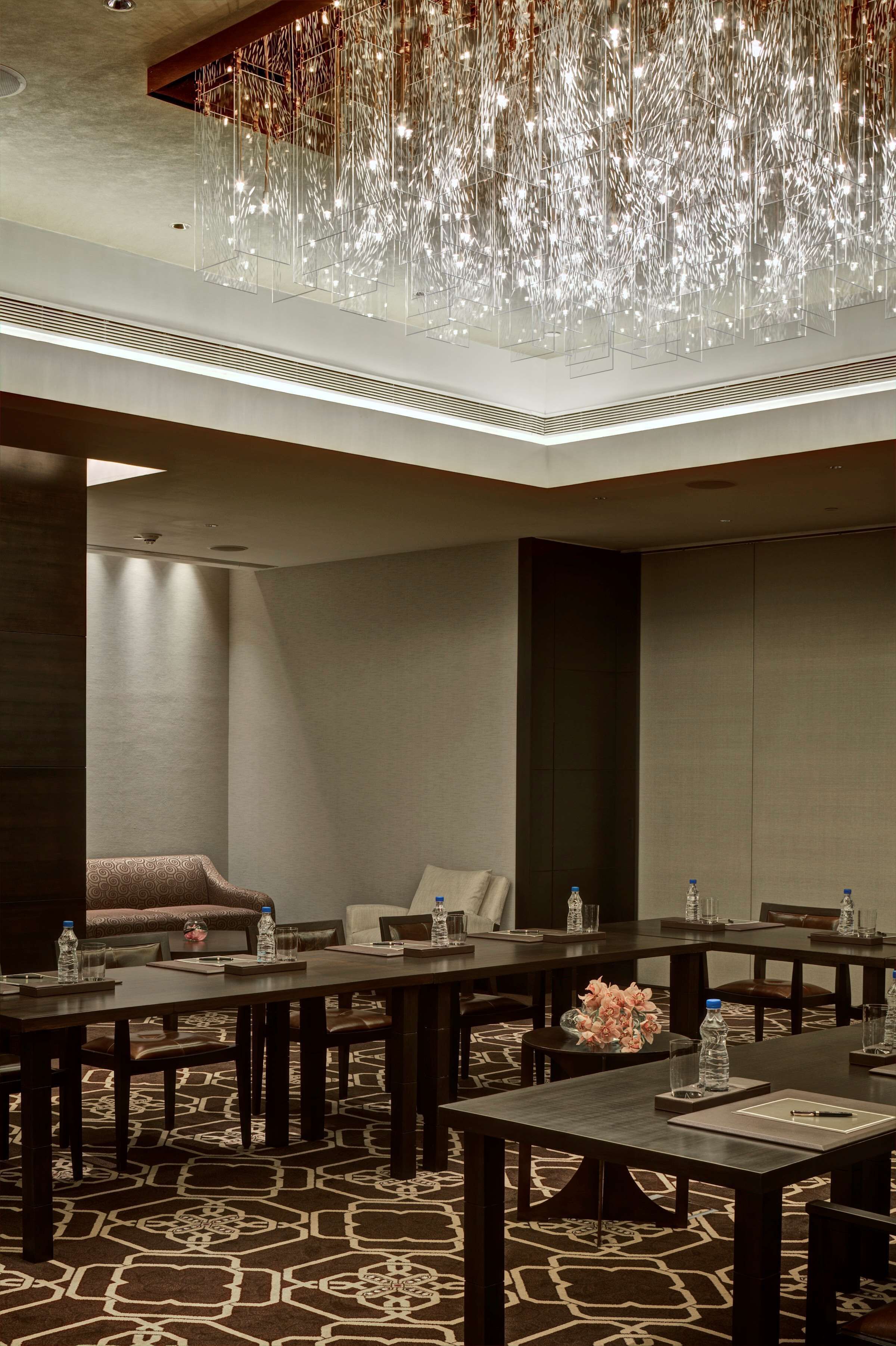 A conference room with tables, chairs, and a chandelier.