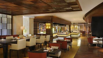 A spacious hotel lobby with multiple seating areas, a central bar, and a well-lit ceiling.