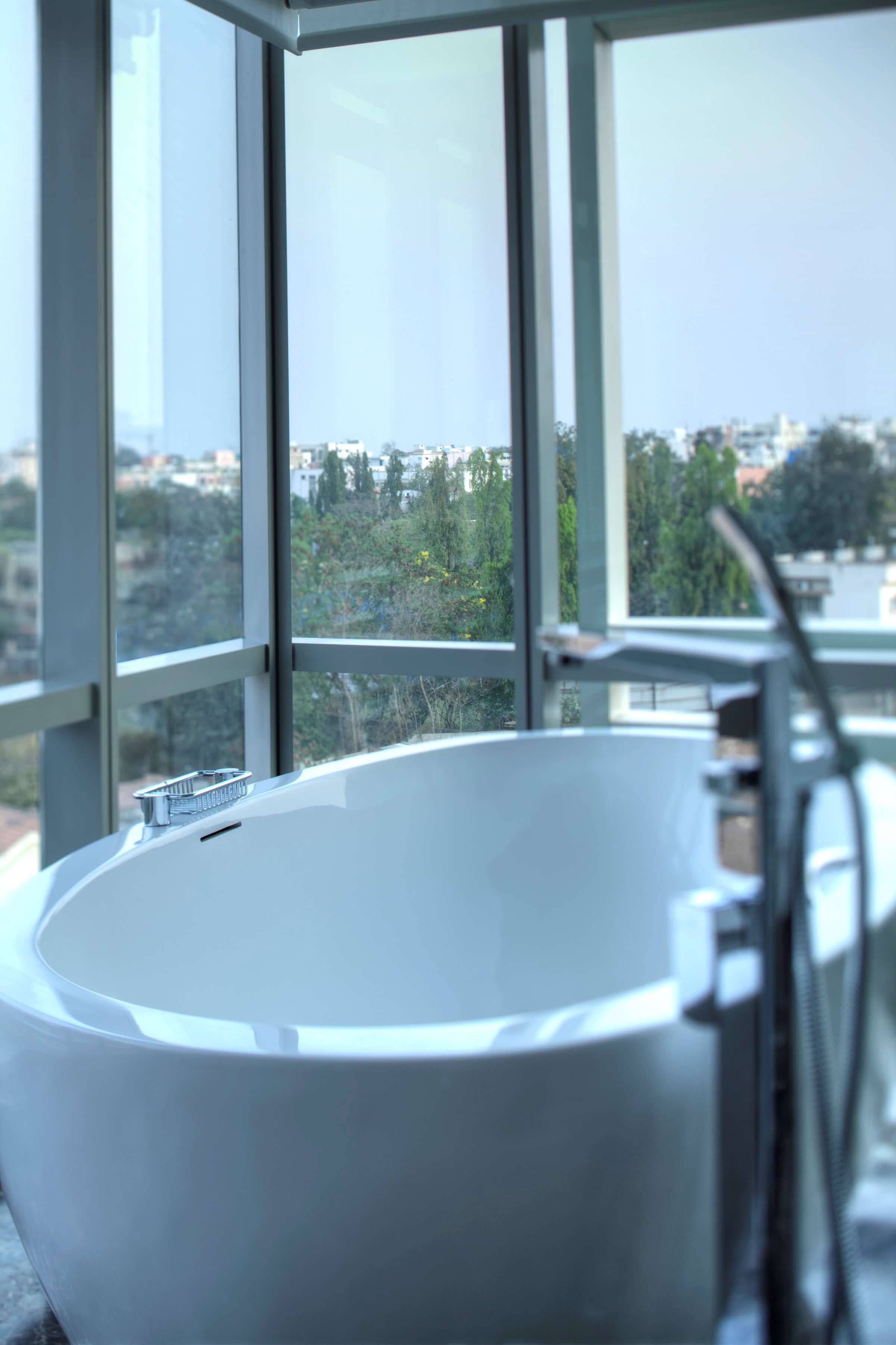 Un baño moderno con una bañera grande, una ventana con vistas a la ciudad y un lavabo de metal.