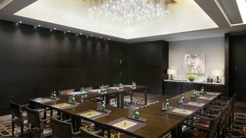 A conference room with a long table, chairs, and a chandelier. There are water bottles and papers on the table.