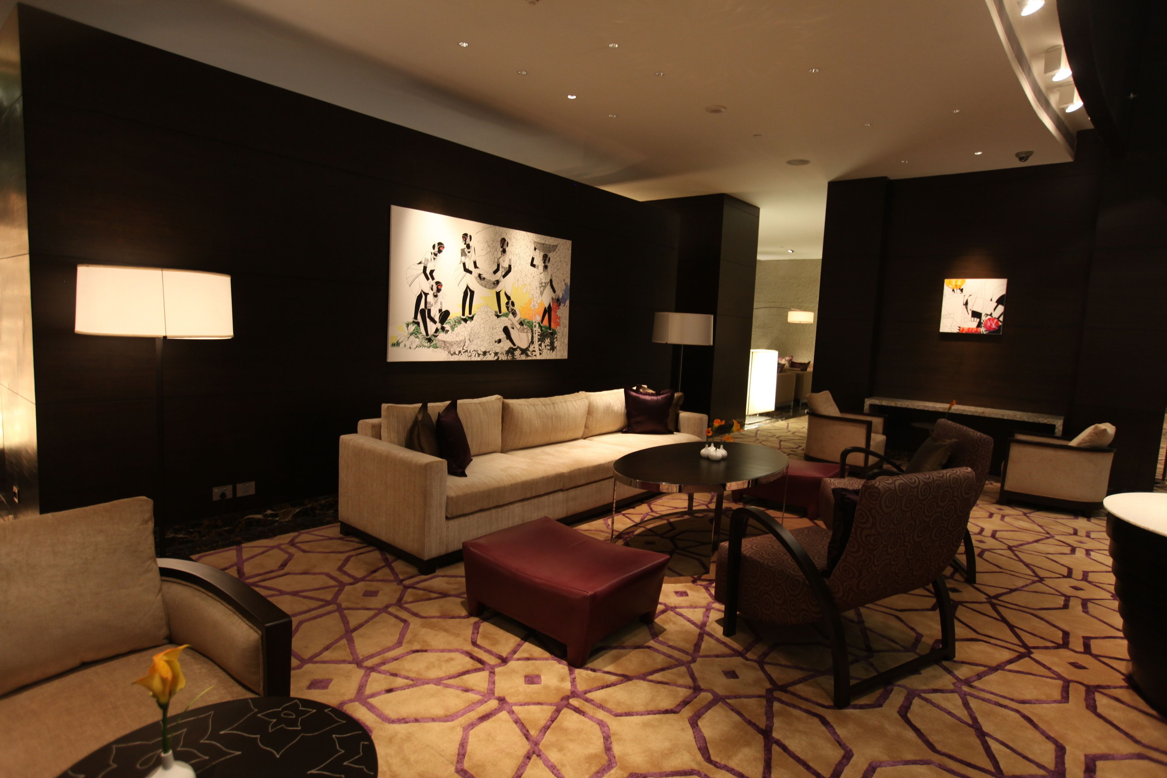 Un hall d’hôtel moderne avec un canapé, un pouf, des fauteuils, une table basse et des œuvres d’art accrochées aux murs.
