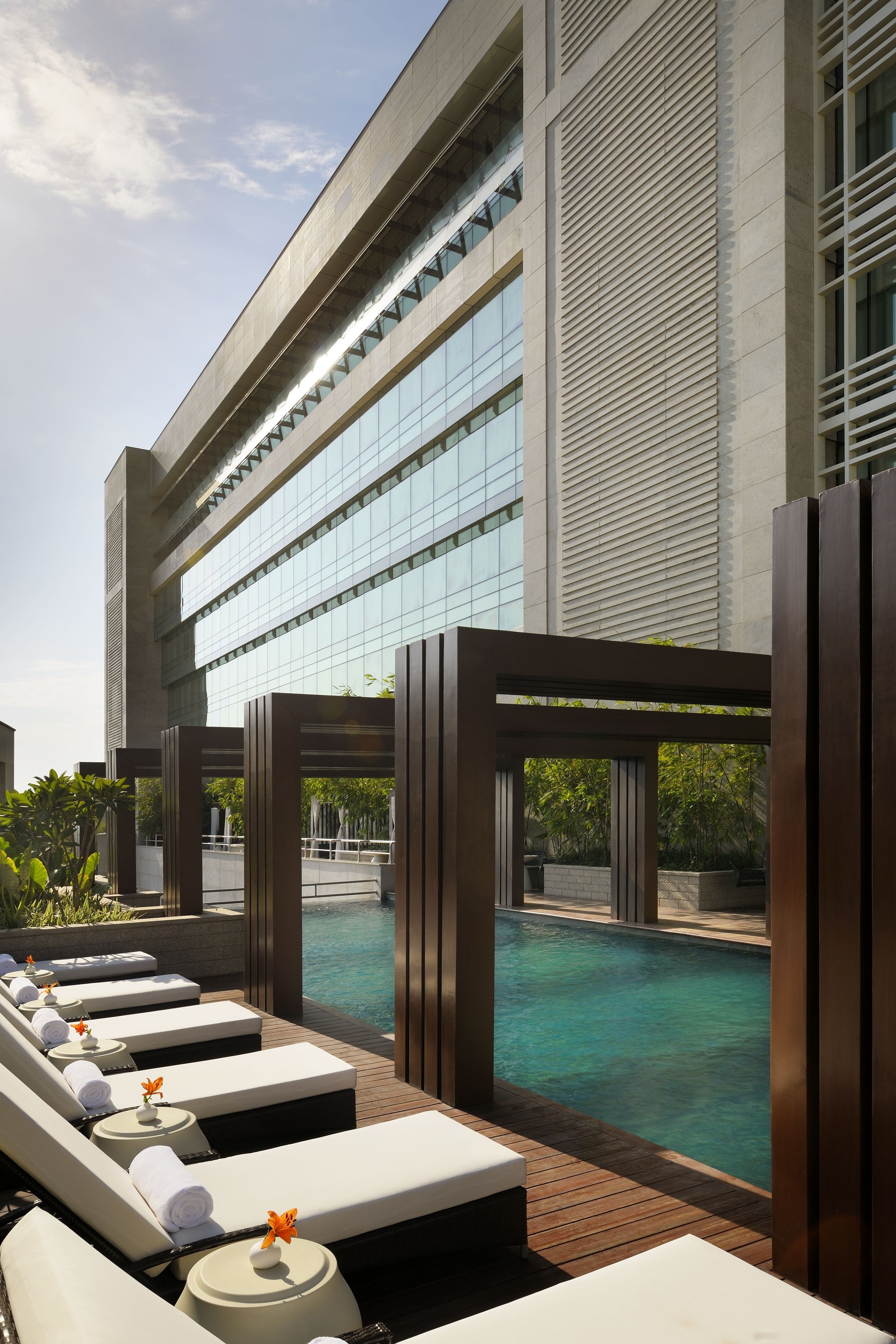 A poolside area with lounge chairs and a view of a building with large windows.
