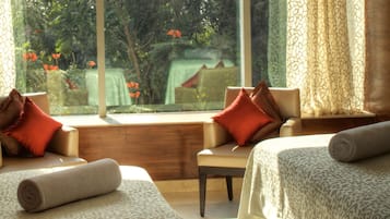 Guest room with a view of lush greenery and a distant building, featuring two beds and a comfortable seating area.