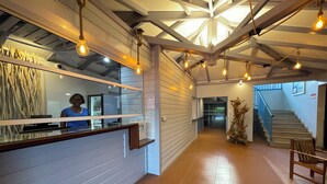 A reception area with a counter, a staircase, and a large window. - Karaibes Residence (Le Gosier)