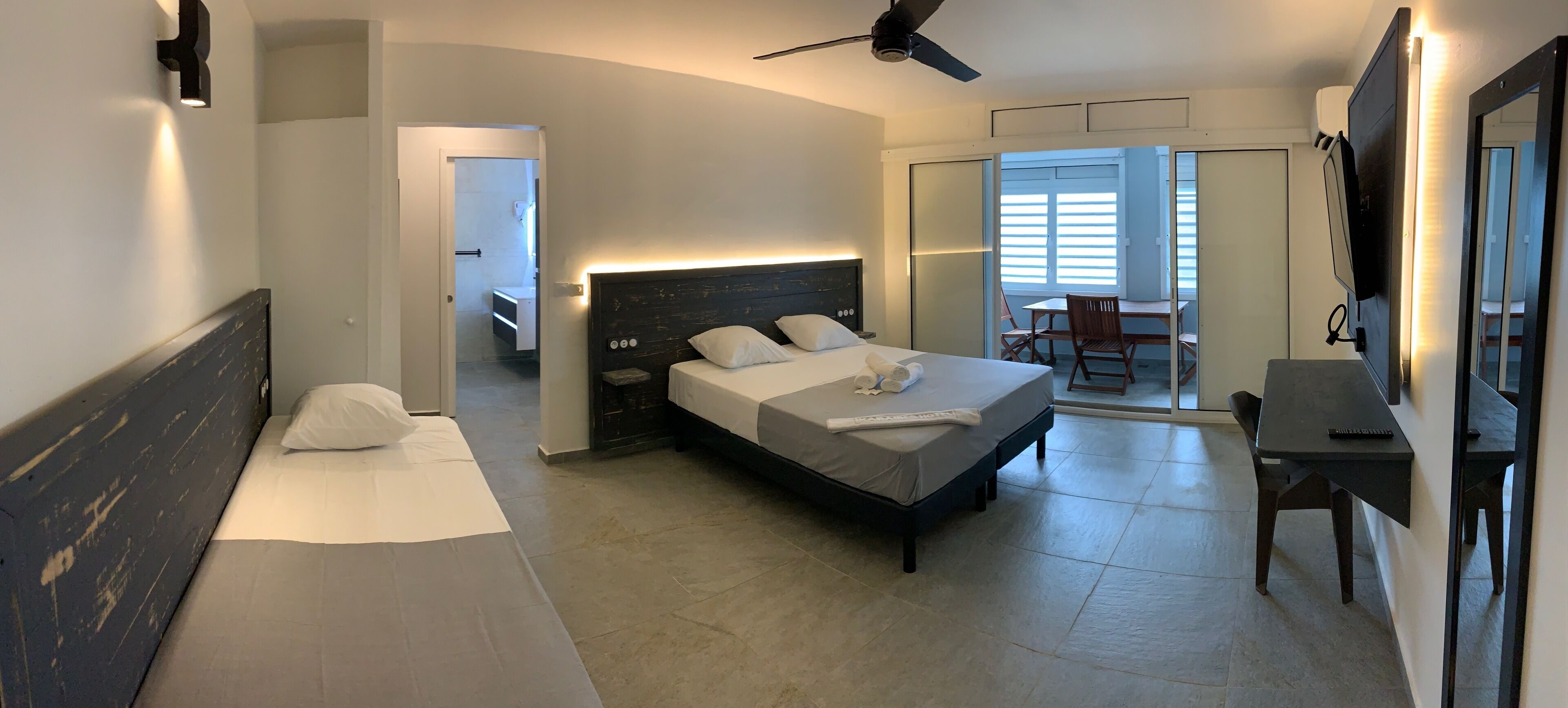 Una habitación de hotel moderna con una cama grande, un escritorio y un balcón con vistas.