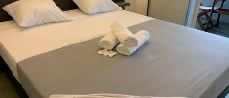 A hotel room with a bed, pillows, and a towel with the hotel's name.
