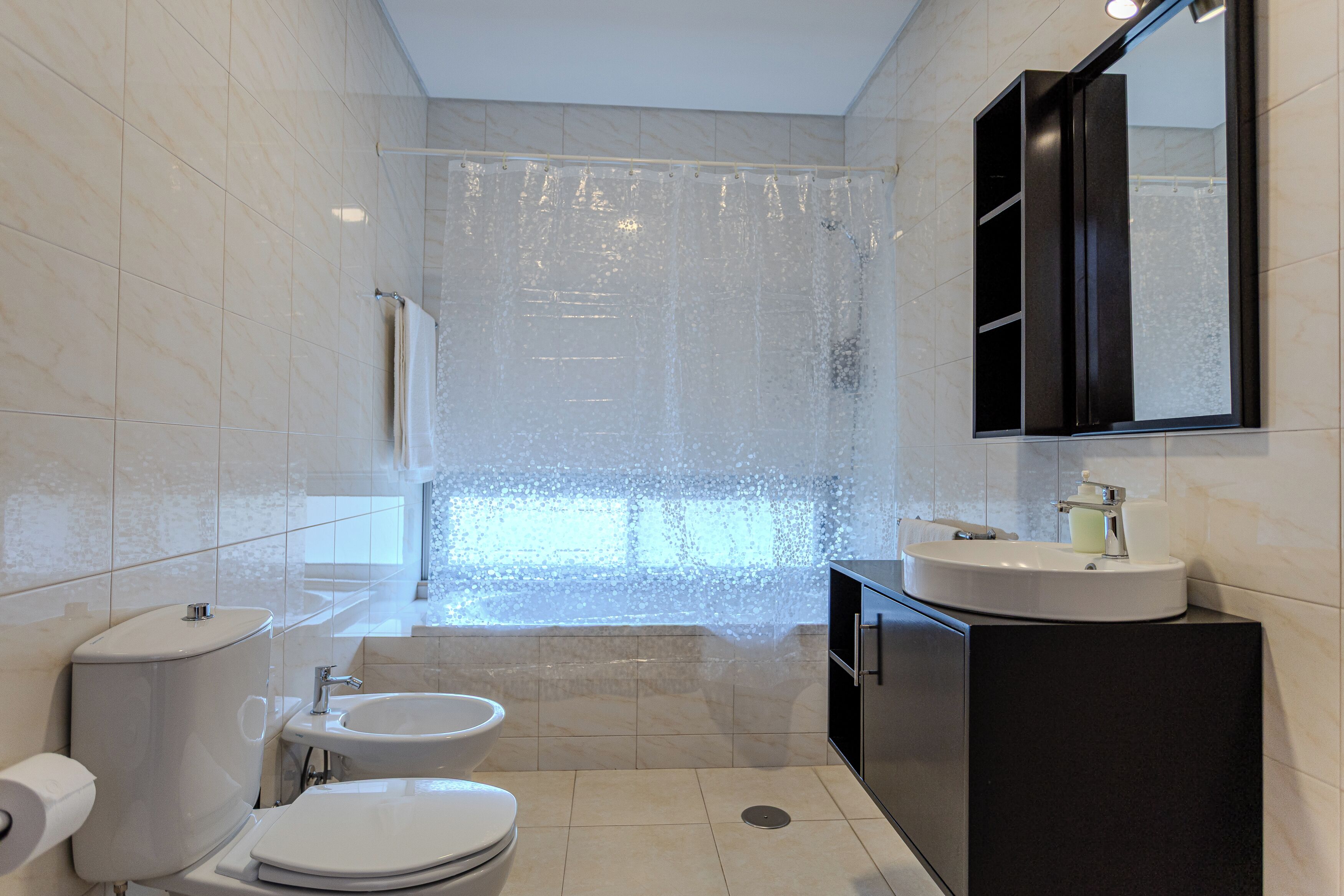 Un baño moderno con inodoro, lavamanos y cortina de ducha.