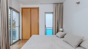 Ein Schlafzimmer mit einem großen Bett, einer Schiebetür, einem Holzschrank und einem Nachttisch mit einer Lampe.