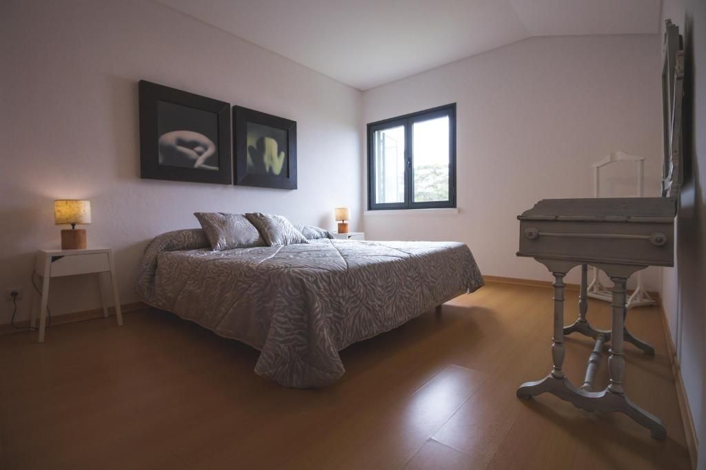 A bedroom with a bed, two bedside lamps, a window, and a piano.
