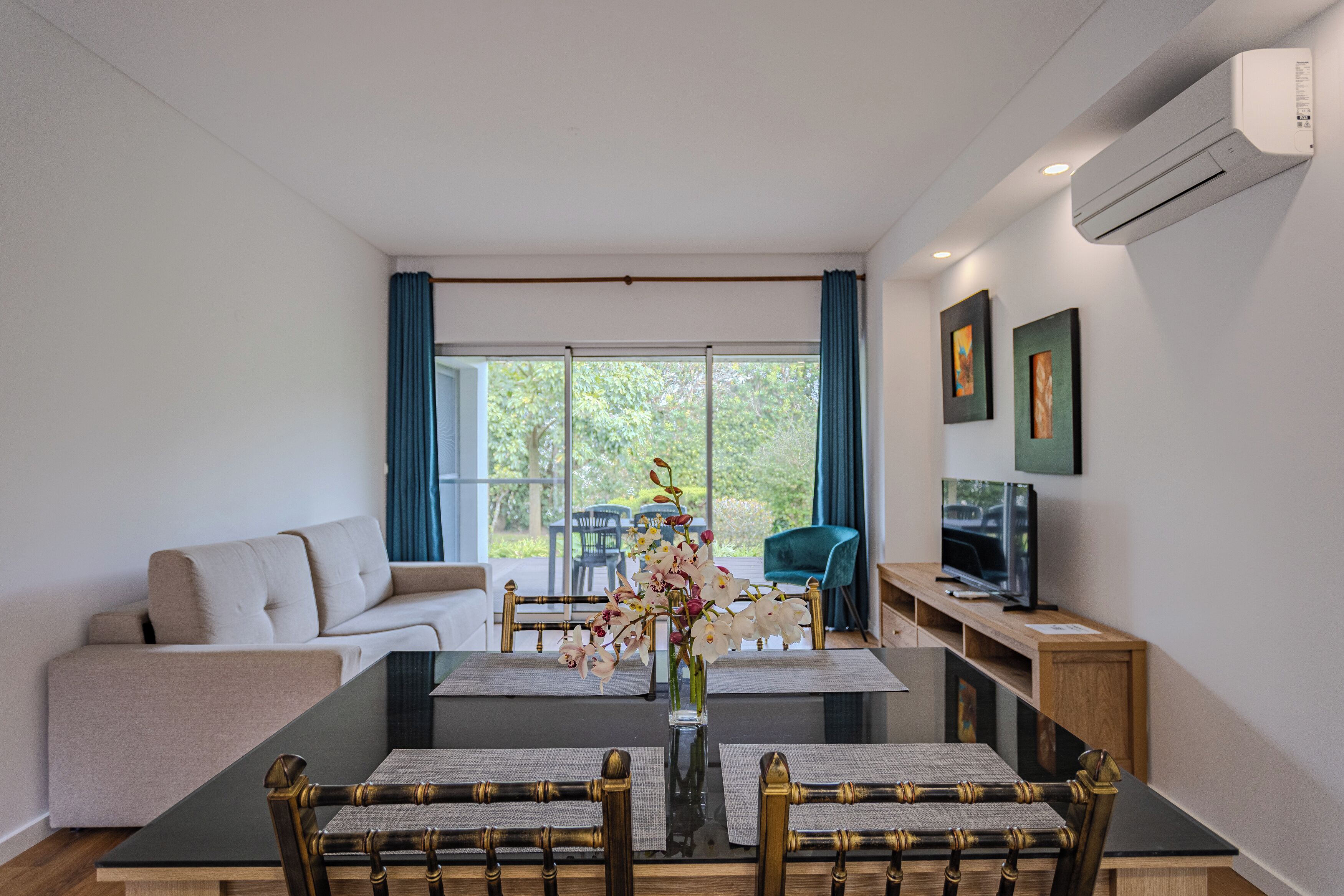 Een moderne woonkamer met een bank, eettafel, stoelen, een televisie en kunst aan de muur.