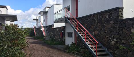 A pathway leading to a row of modern buildings with red railings and stone walls.