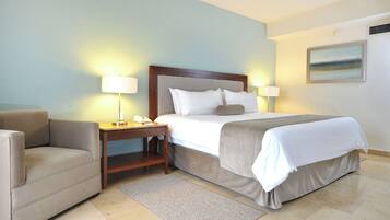 A hotel room with a bed, a sofa, a nightstand, and a painting on the wall.