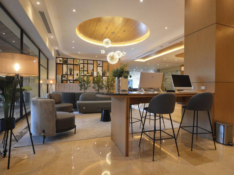 A modern lobby with a curved ceiling, a reception desk, bar stools, and a seating area with sofas and a coffee table.