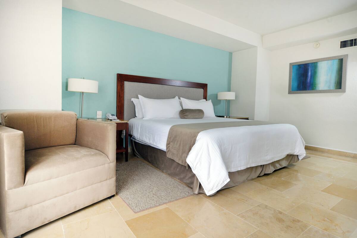 Ein Hotelzimmer mit Bett, Sofa, Nachttisch und Lampe.