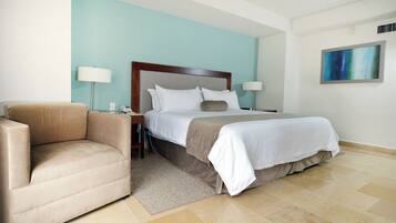 A hotel room with a bed, a sofa, a nightstand, and a lamp.