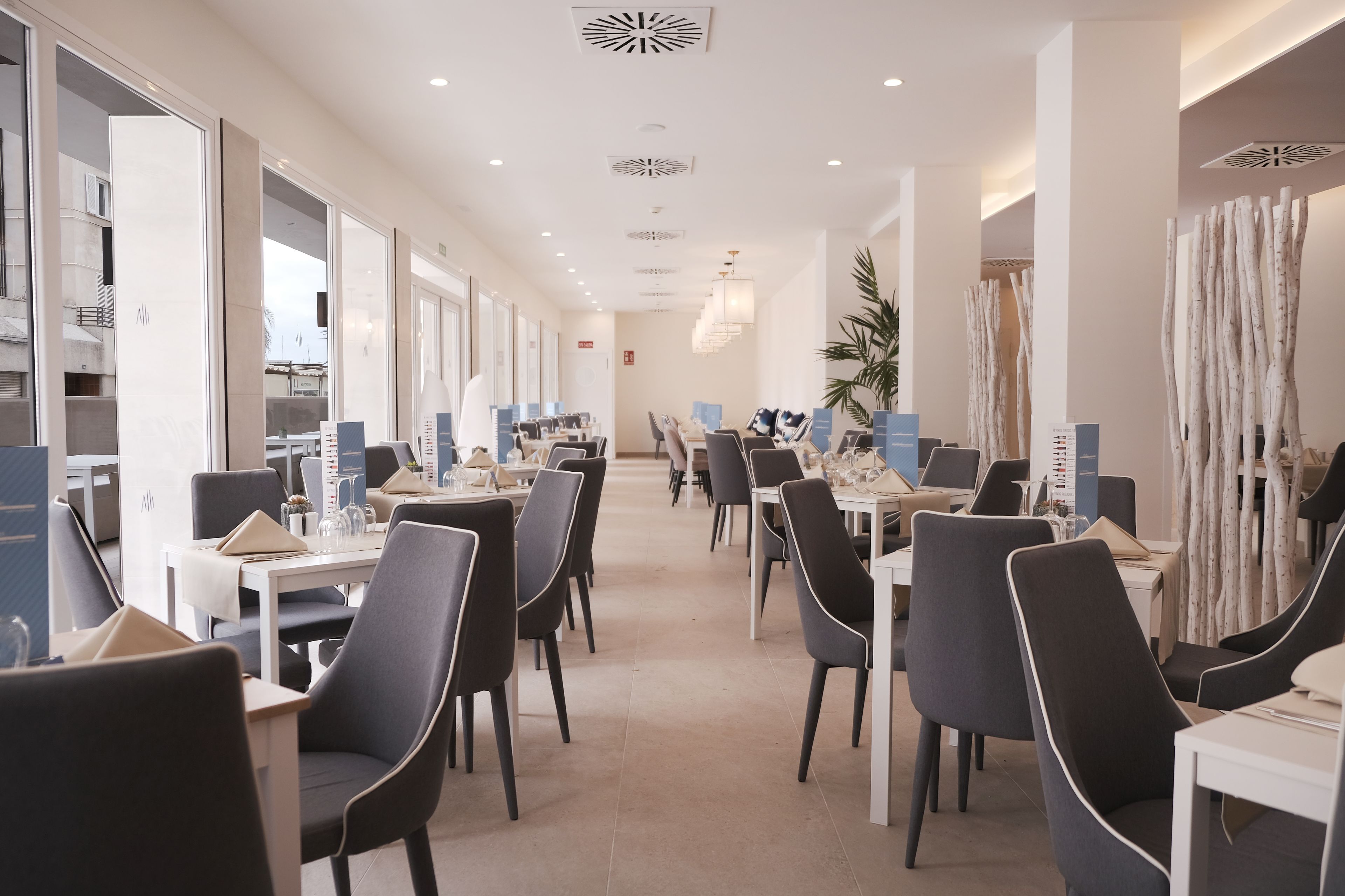 Un espace de restauration moderne dans un hôtel, avec de longues tables, des chaises noires et un design épuré et minimaliste.