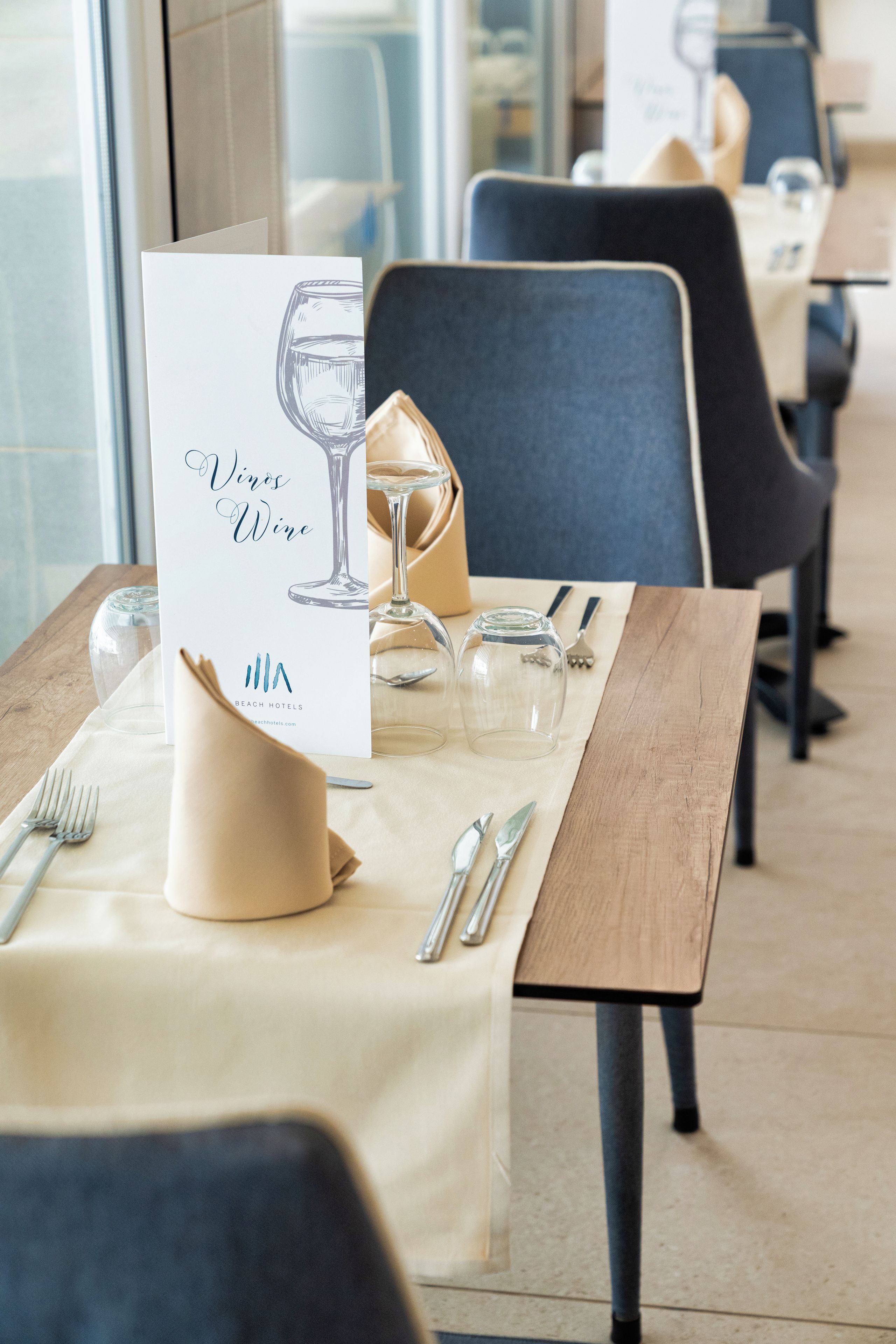 A restaurant table set with a menu, wine glass, and cutlery.